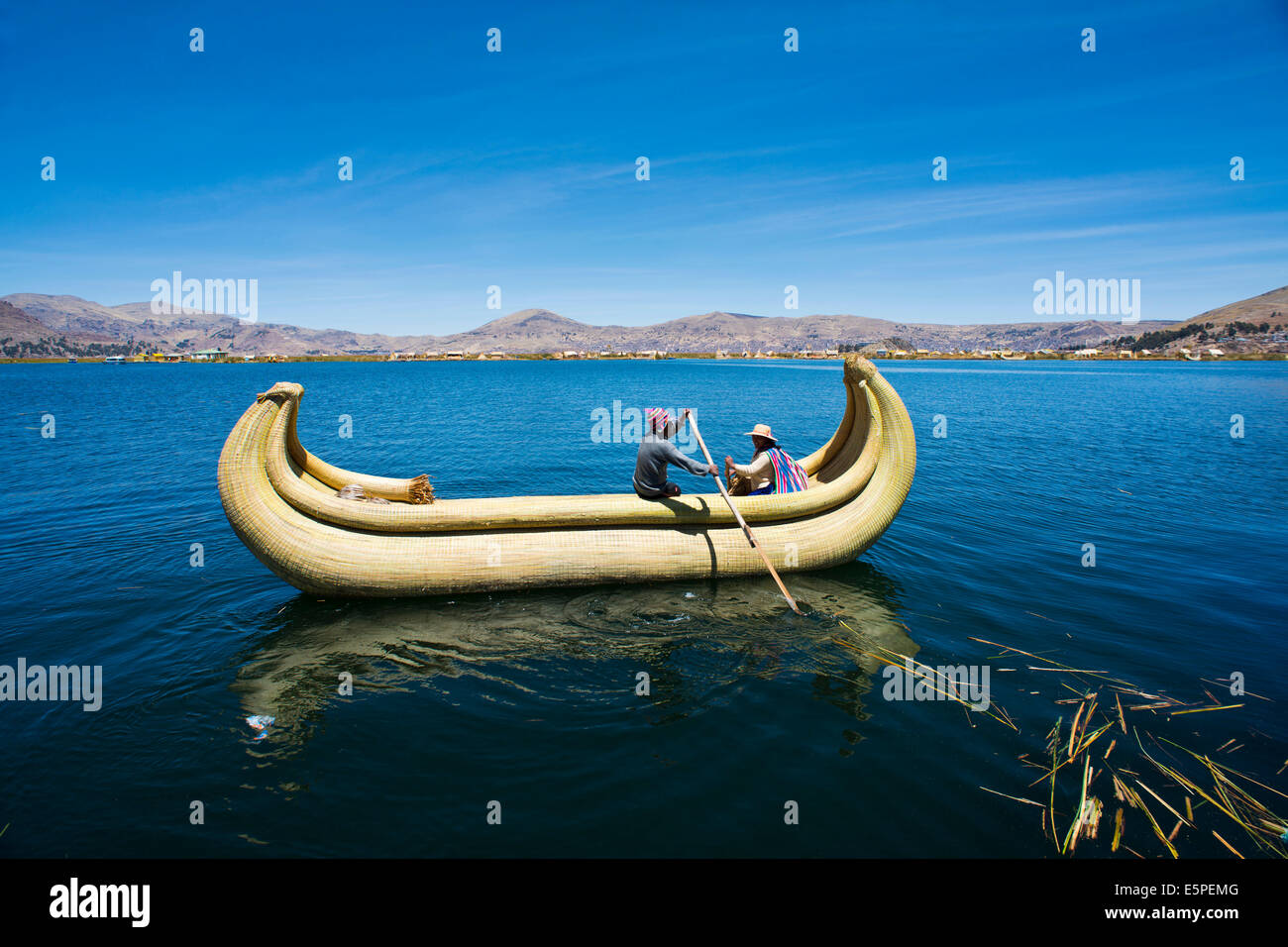 Two local in a traditional rowing boat of Totora reed on Lake Titicaca, Peru Stock Photo