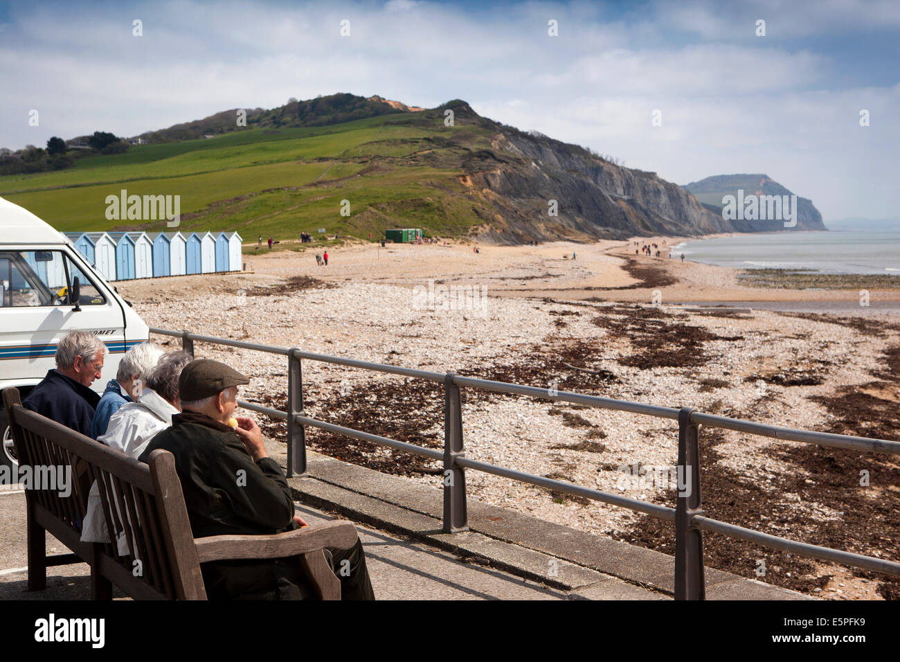 UK England, Dorset, Charmouth, visitors sat in sun overlooking the beach Stock Photo