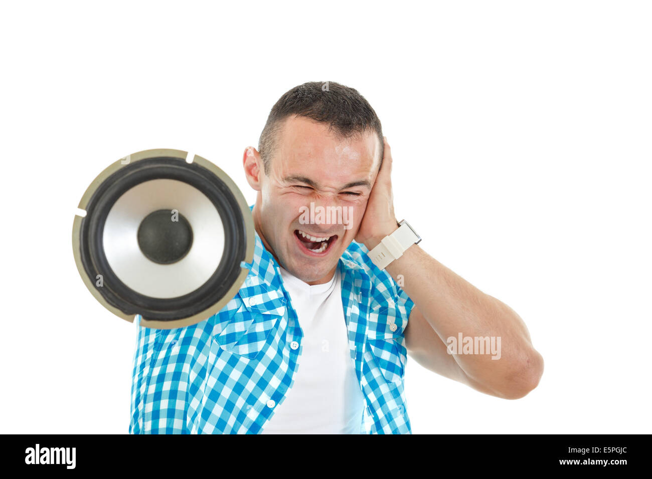 Man listening to loud music holding speaker and covering his ears Stock