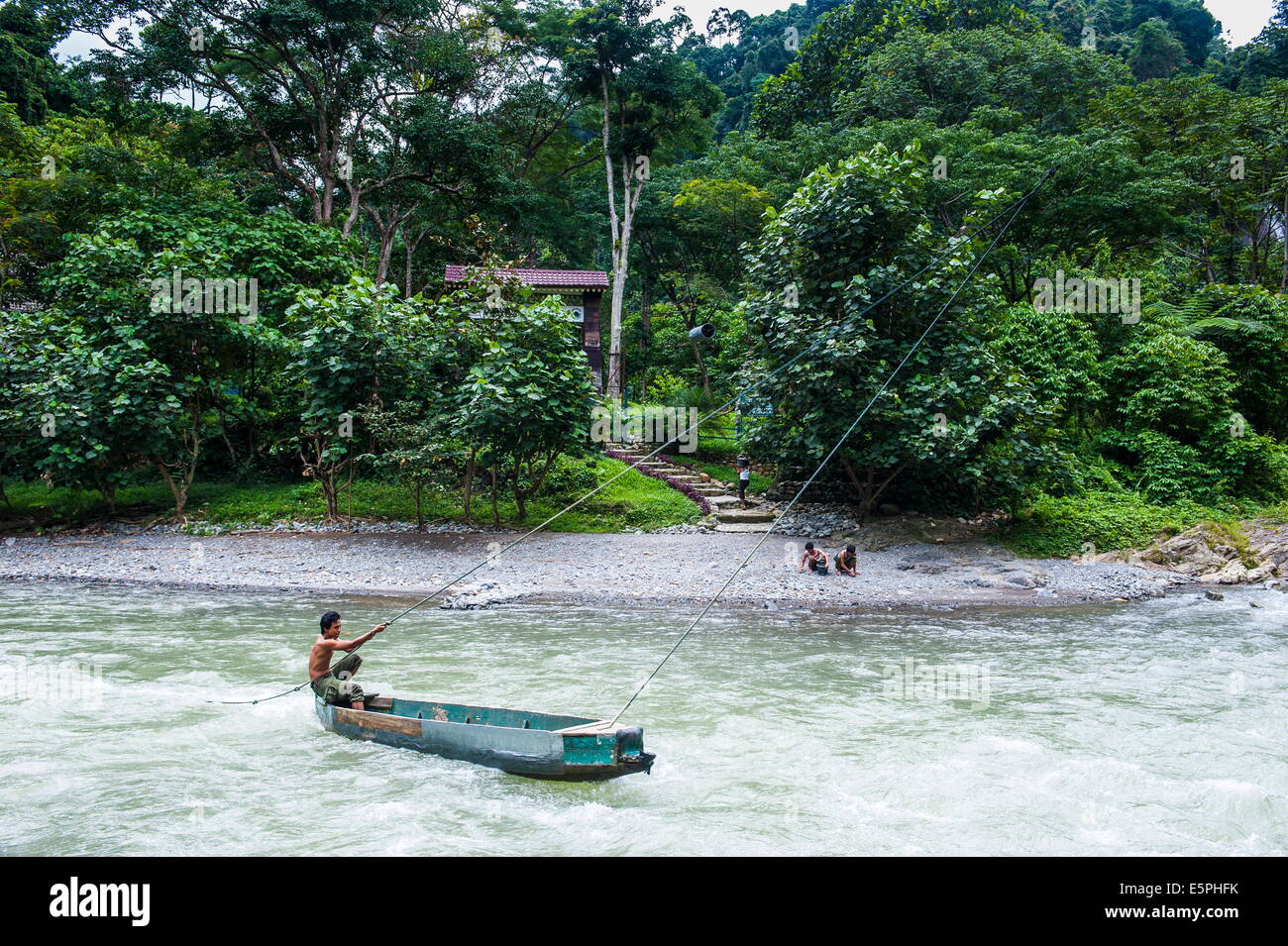 Man on the Bohorok River, transporting tourist to the Bukit Lawang Orang Utan Rehabilitation station, Sumatra, Indonesia Stock Photo