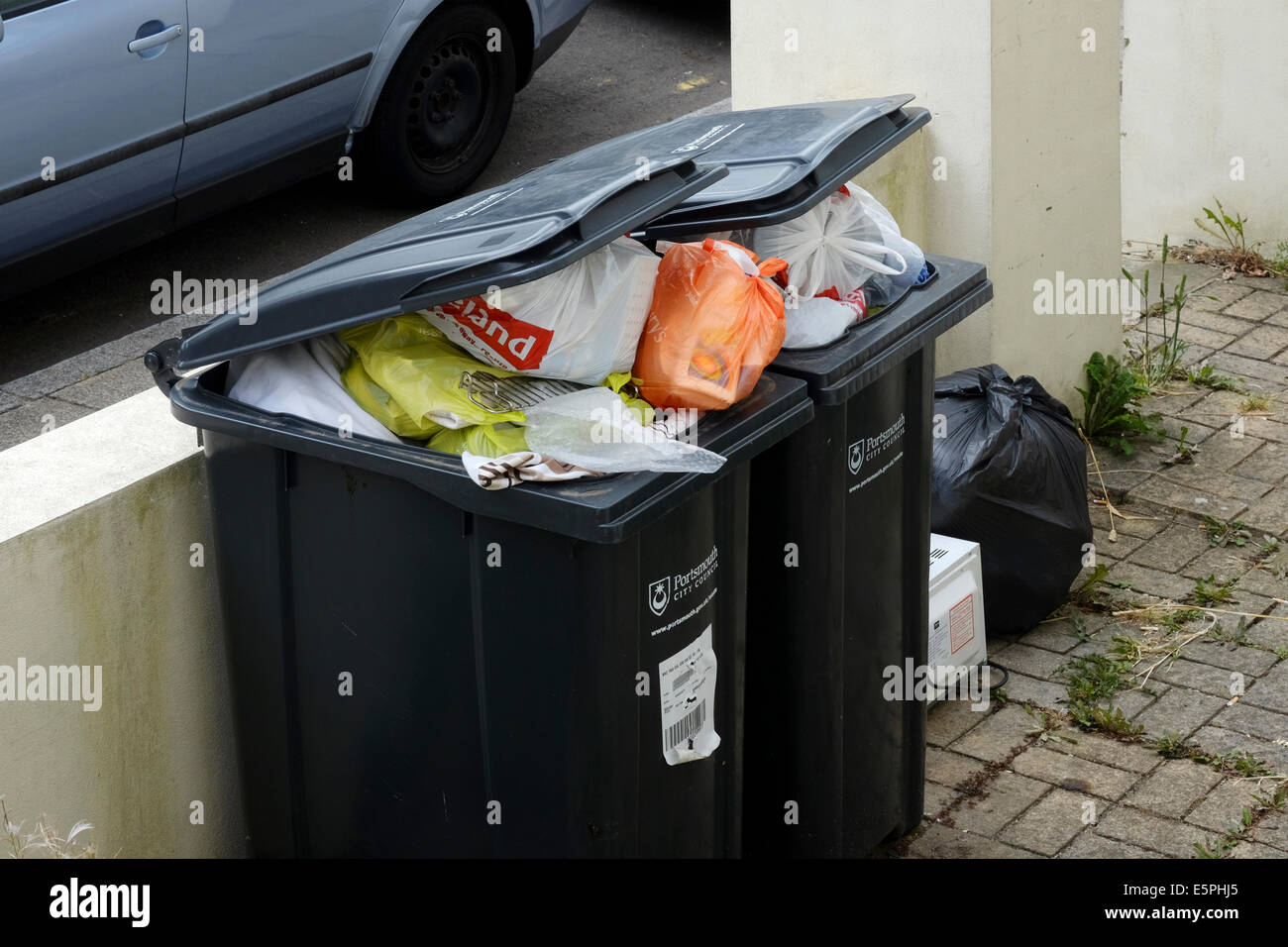 domestic wheelie bins overflowing with rubbish awaiting collection and emptying england uk Stock Photo
