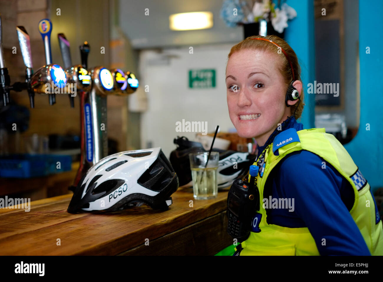 a female police community support officer smiling in a bar drinking fruit juice whilst on official police business uk Stock Photo
