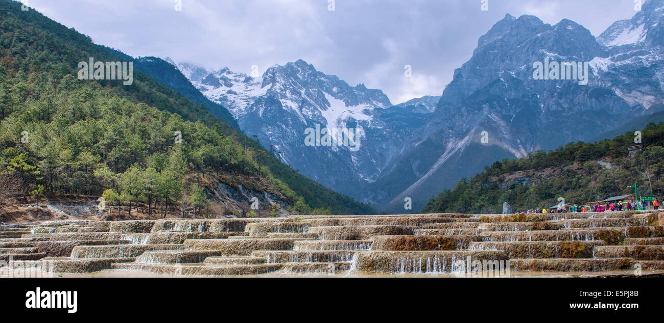 View of cascading waterfalls and mountain backdrop, including Yu Long Xue Shan at White Water River, Lijiang, Yunnan, China Stock Photo