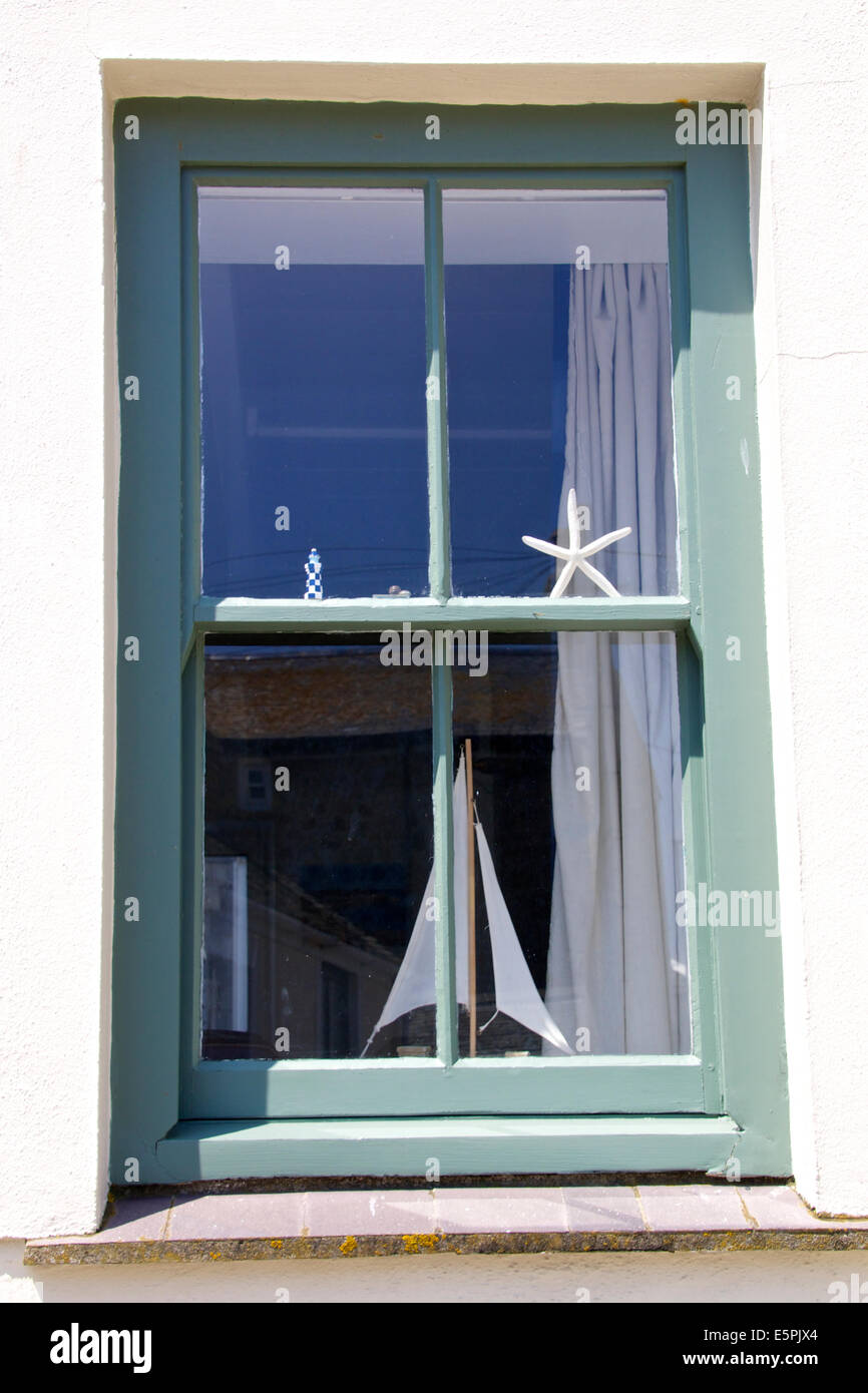 A small cottage in St Ives Cornwall South West England. Sash window painted green with star fish and boat ornaments in window Stock Photo