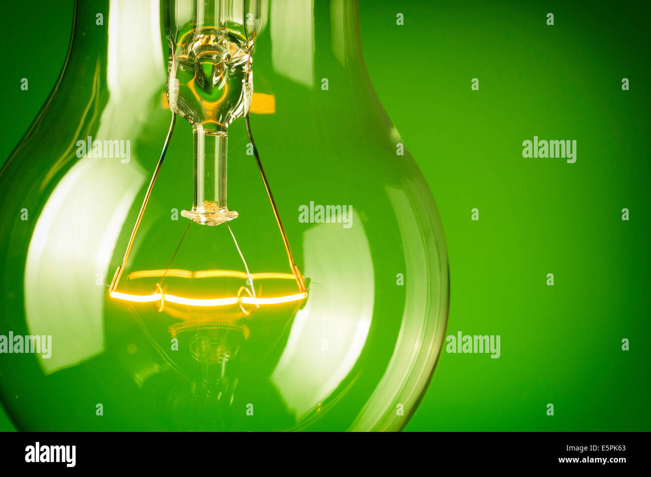 Close up glowing light bulb on green background Stock Photo