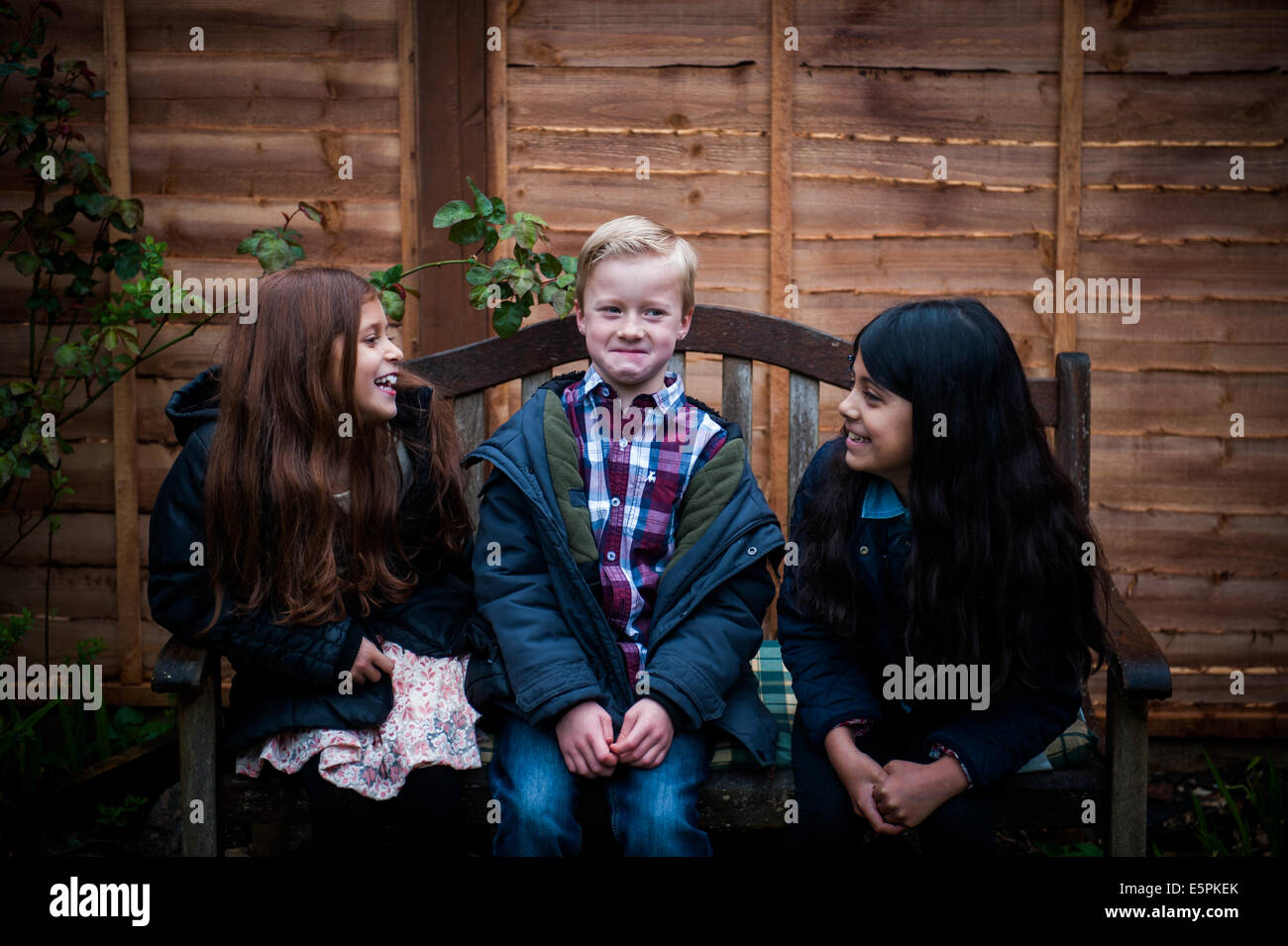 embarrassed boy in the middle while girls talk Stock Photo