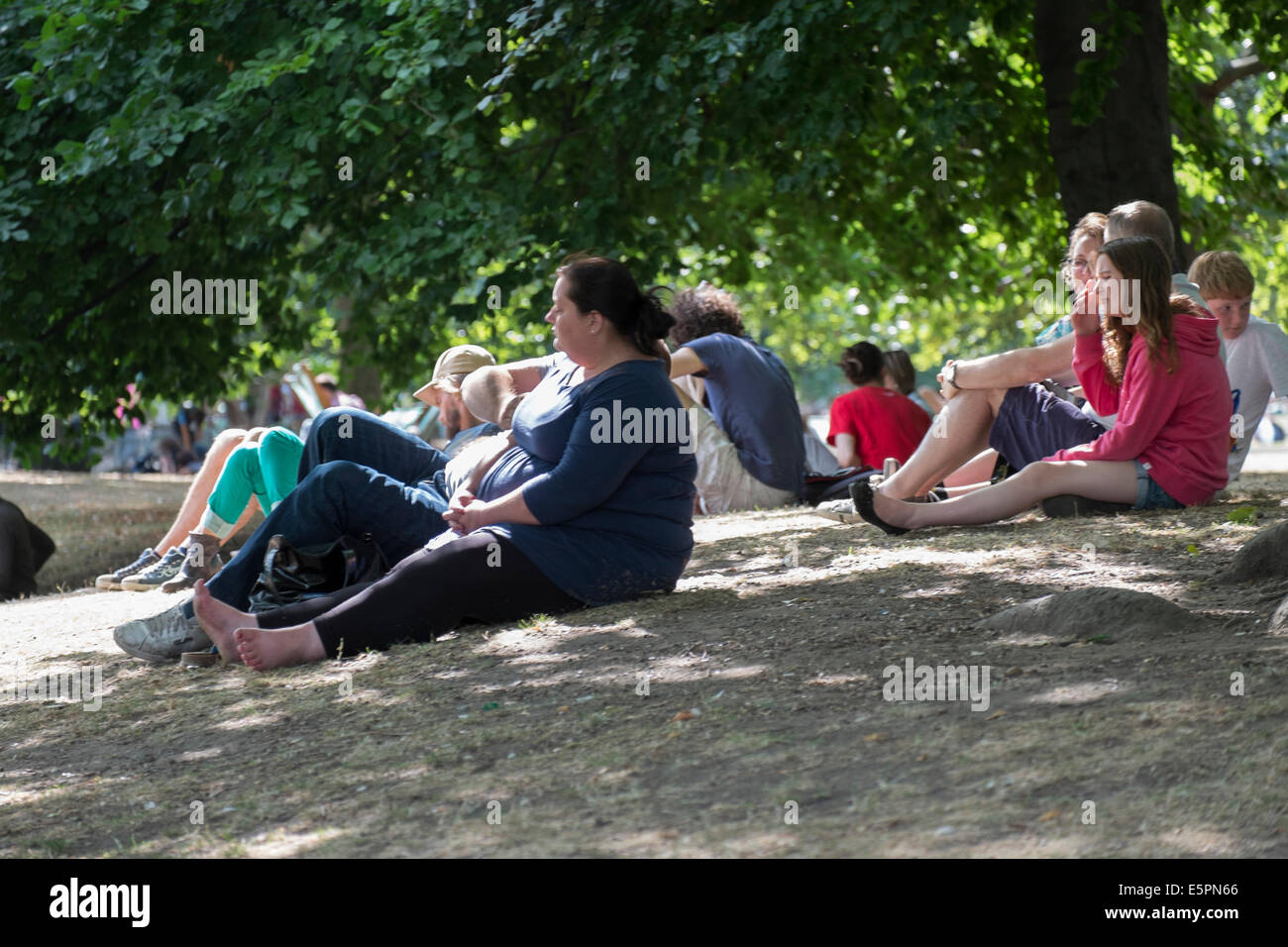 People taking shade during the midday sun in London's St James Park, UK Stock Photo