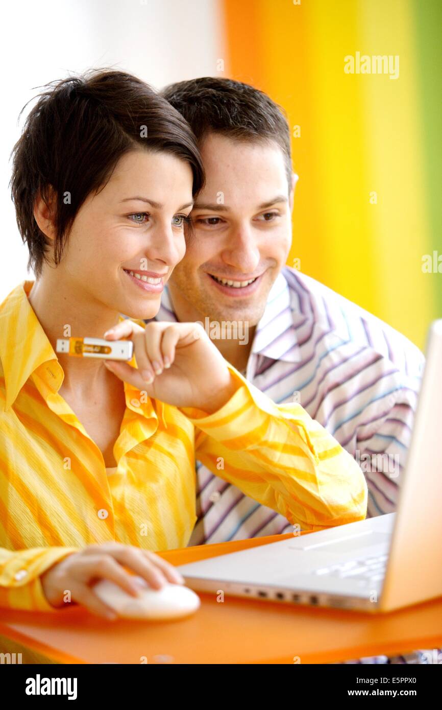 Couple with laptop computer using USB key to store digital data. Stock Photo