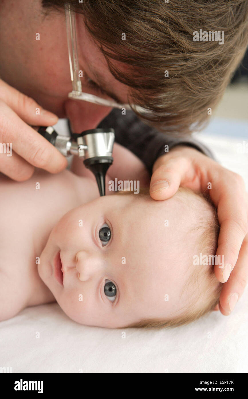 Pediatrician examining the ears of a 2monthold baby girl with an