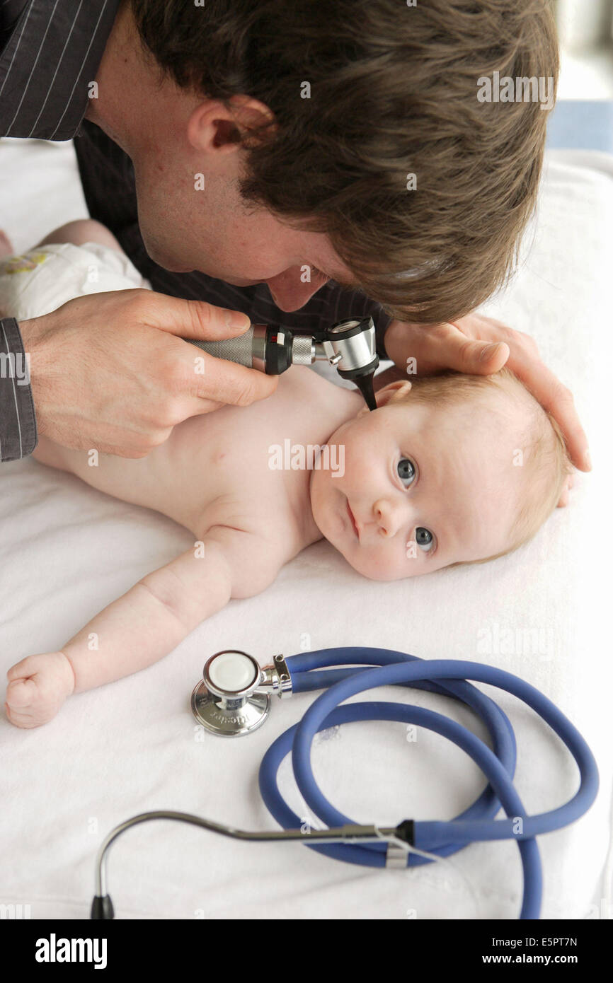 Pediatrician examining the ears of a 2monthold baby girl with an