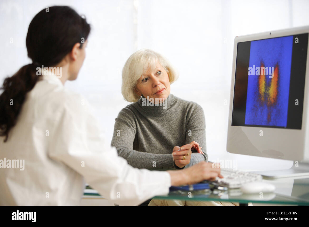 Doctor discussing a thyroid gland scintigram with a female patient. Stock Photo