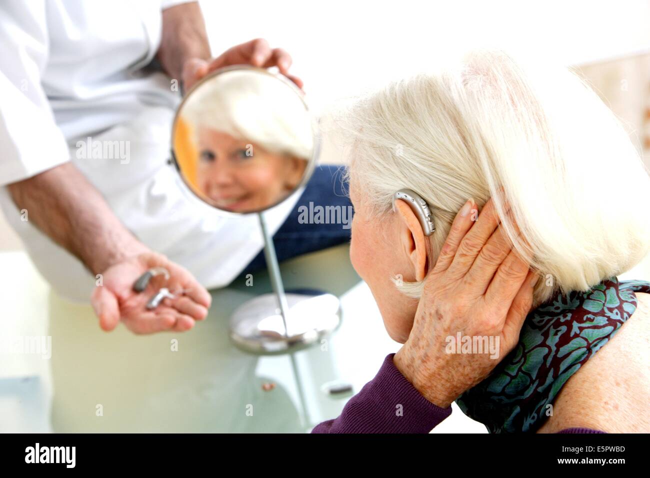Hearing aid specialist showing elderly hires stock photography and