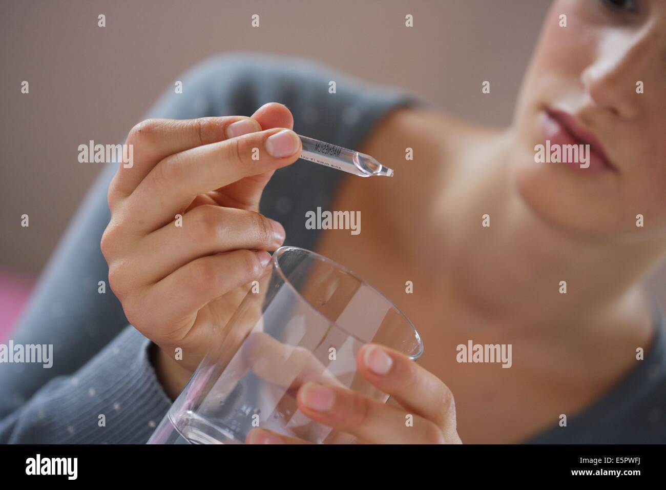 Woman taking a glass ampoule of trace elements (magnesium). Stock Photo