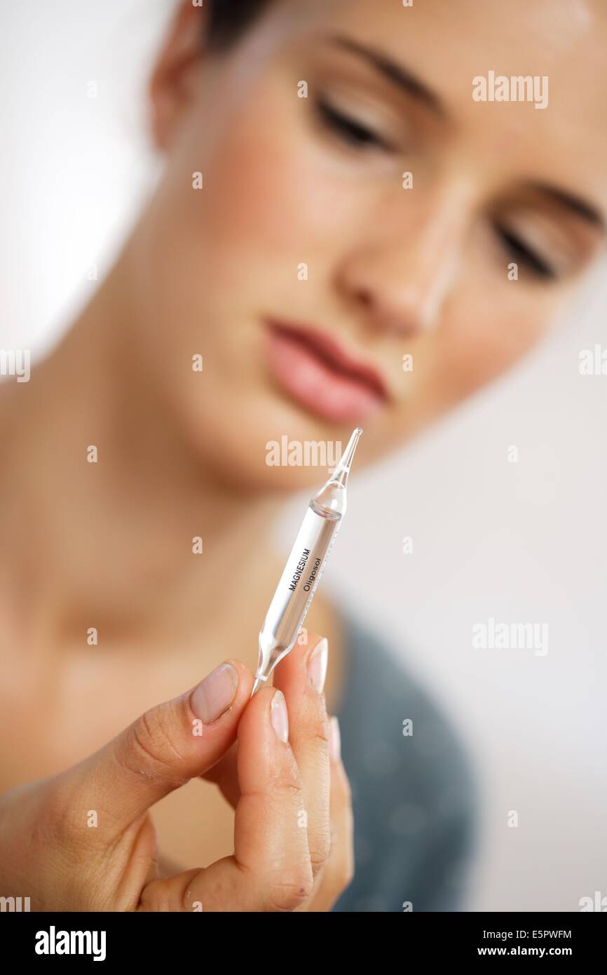 Woman taking a glass ampoule of trace elements (magnesium). Stock Photo