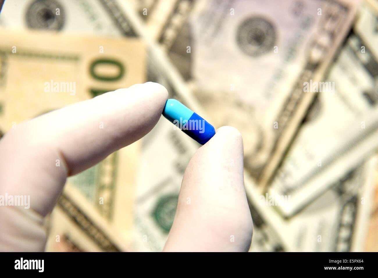 Hand holding drug capsule with dollars. Stock Photo