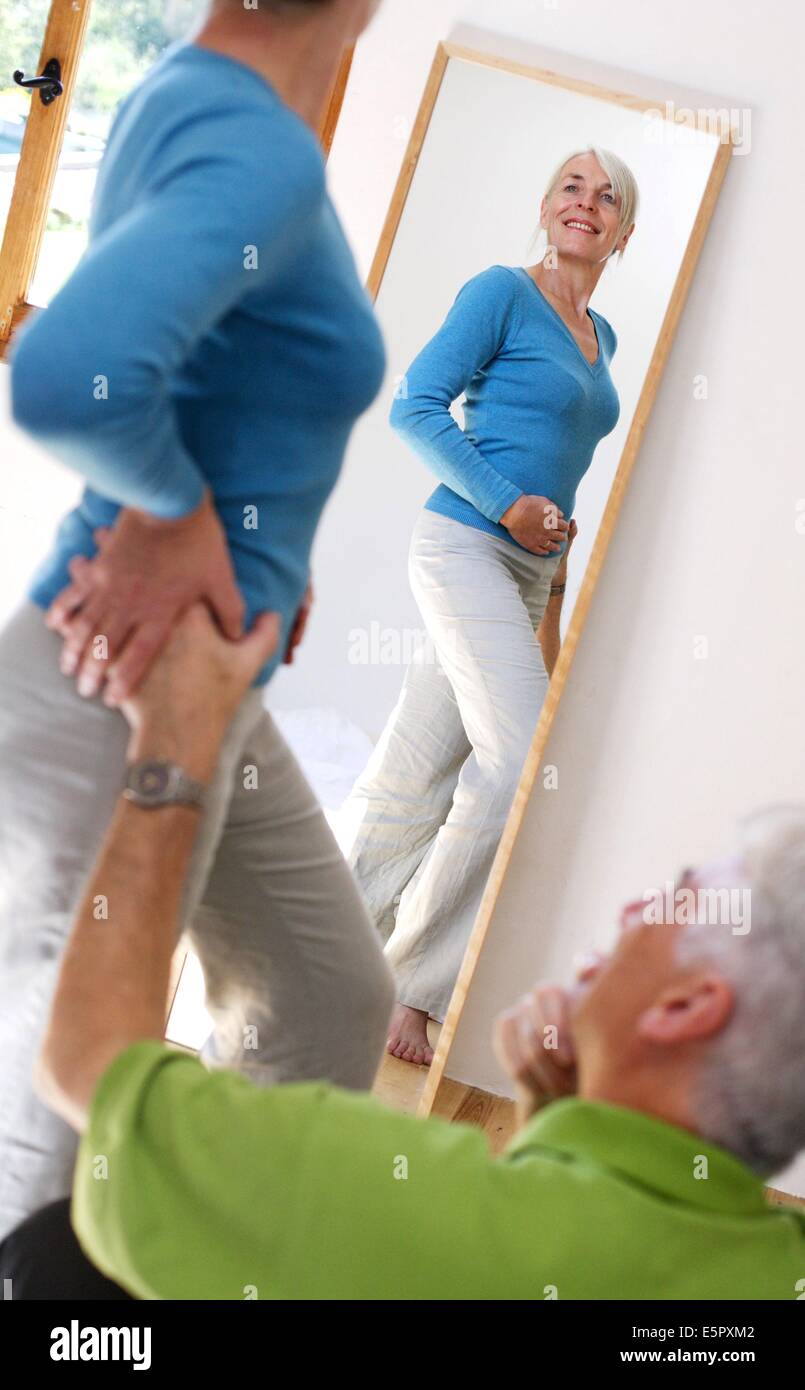 Senior woman looking at her body in a mirror Stock Photo - Alamy