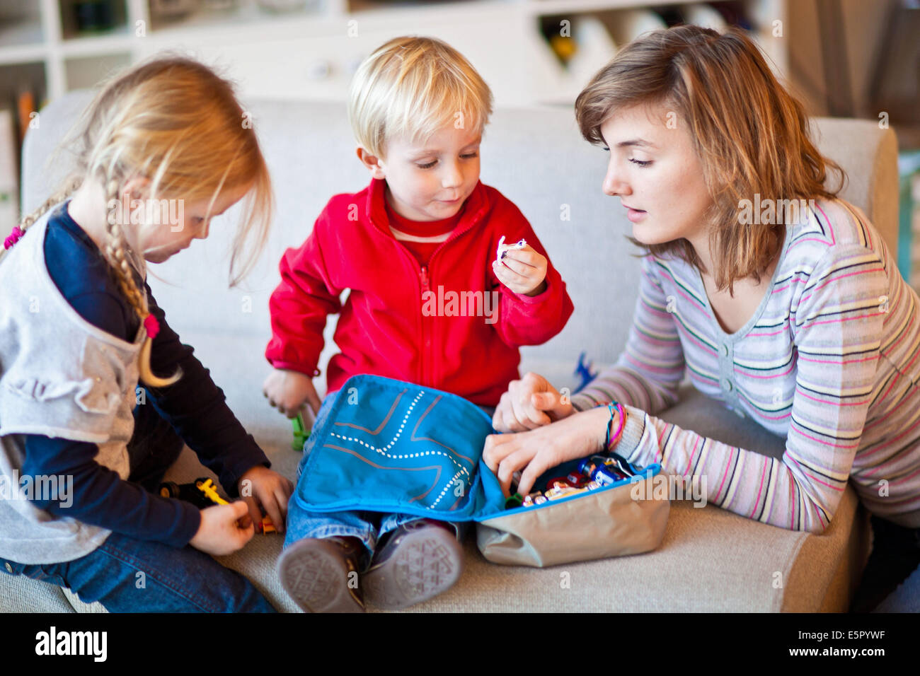Teenage girl and 3-year-old boy playing with figurines. Stock Photo