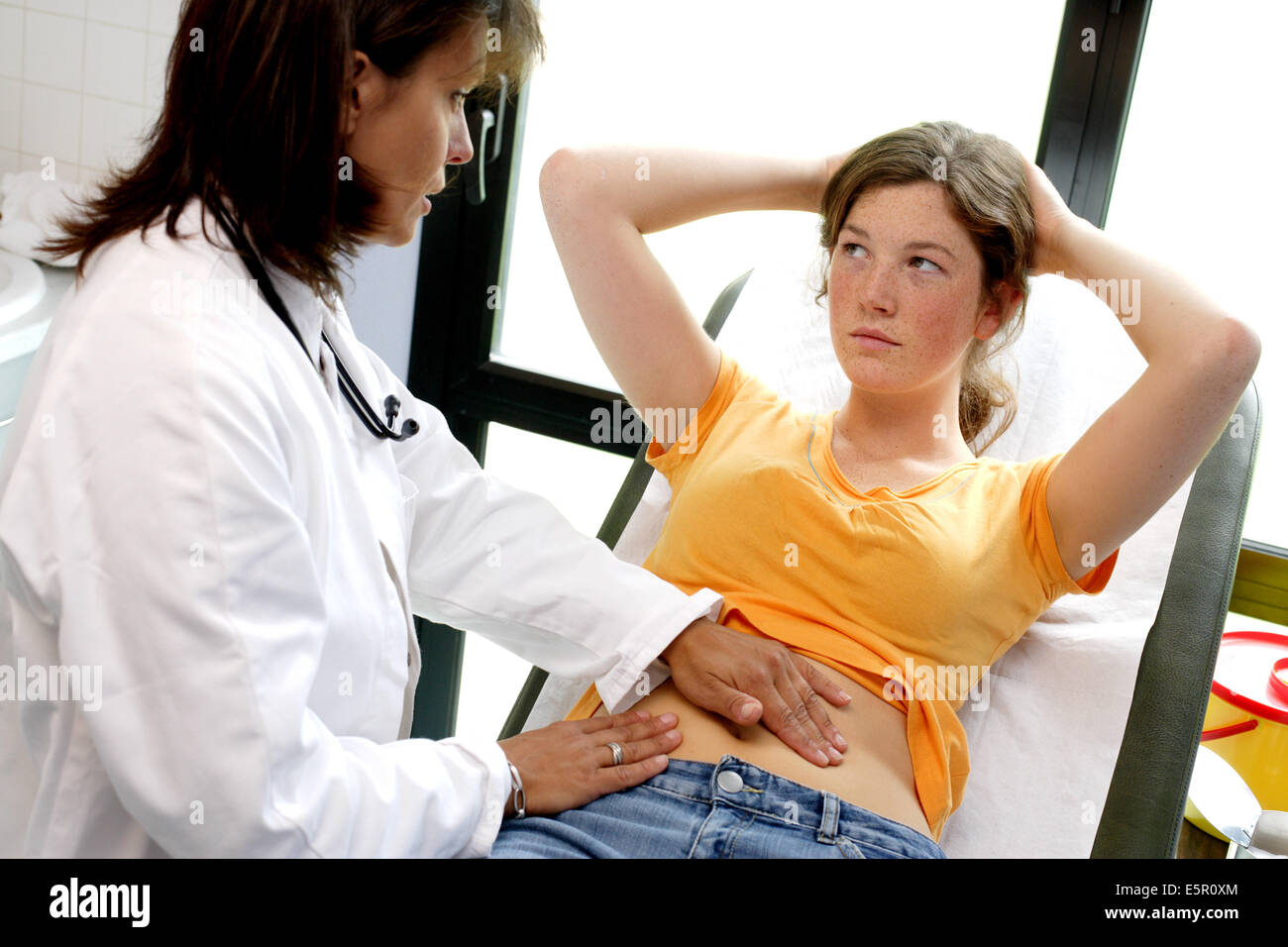 Doctor examining the abdomen of a female teenager by palpation Stock