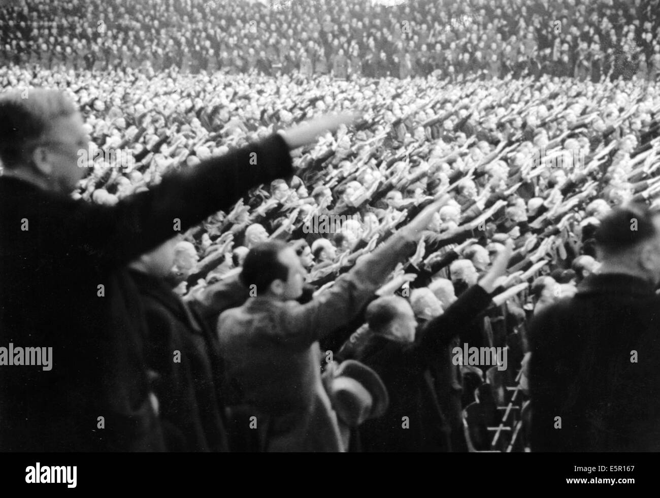 A large group of people listen to the speech by Propaganda Minister Joseph Goebbels, who called for 'total war' at the Sportpalast in Berlin, Germany, 18 February 1943. The original Nazi propaganda text on the back of the picture: 'Special event by the NSDAP. Gau Berlin in the Sportspalast with a speech by the Gauleiter of Berlin, Reich Minister Dr. Goebbels. Our picture shows thousands of spectators showing their never-ending consent as Reich Minister Dr. Goebbels asked the listeners, a group that embodied the entire German people from all ranks, for approval of the measures related to total  Stock Photo