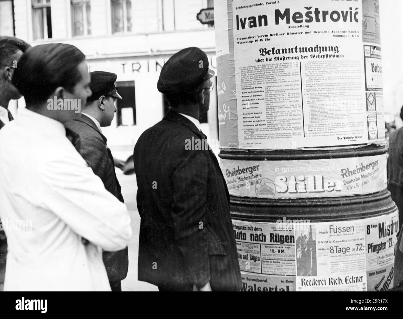 The picture from a Nazi news report shows young men reading the announcement of the draft on an advertizing column in Berlin, Germany, June 1935. On 16 March 1935 against the prohibition by the Treaty of Versailles, the general draft war reinstated in the Third Reich. Fotoarchiv für Zeitgeschichte - NO WIRE SERVICE Stock Photo