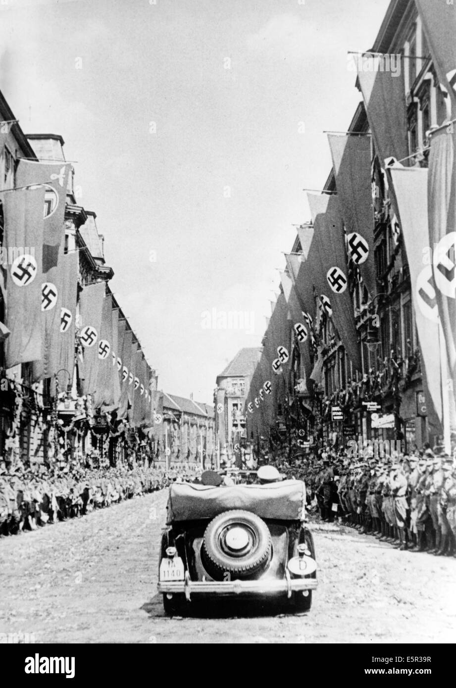 People cheer at the arrival of Hitler's motorcade on Wilhelmplatz in front of a crowd of cheering people as Hitler returns from his Felsennest headquarters after the Armistice of Compiegne was signed that ended the western campaign in France in Berlin, Germany, 06 July 1940. 'The capital of the Reich received the victorious commander with cherring. On Saturday afternoon, the Reichs capital was marked by the return of the leader, the victor of the largest and most brilliant battle in German history. The streets through which the Fuhrer drove were filled with hundreds of thousands of people who  Stock Photo