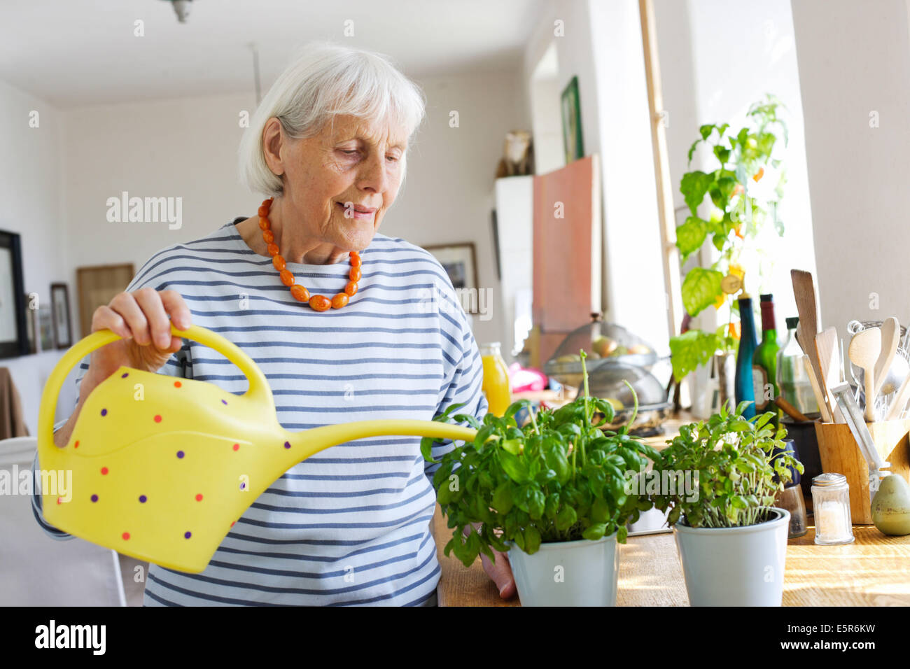 80 year old woman watering her plants. Stock Photo