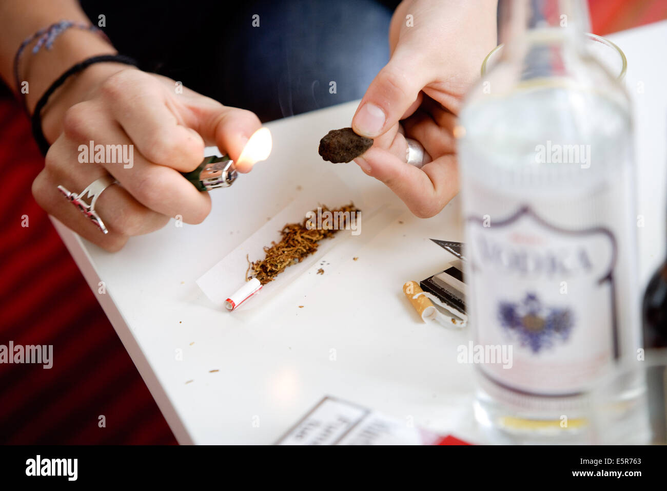 Young person burning hashish to roll a joint. Stock Photo