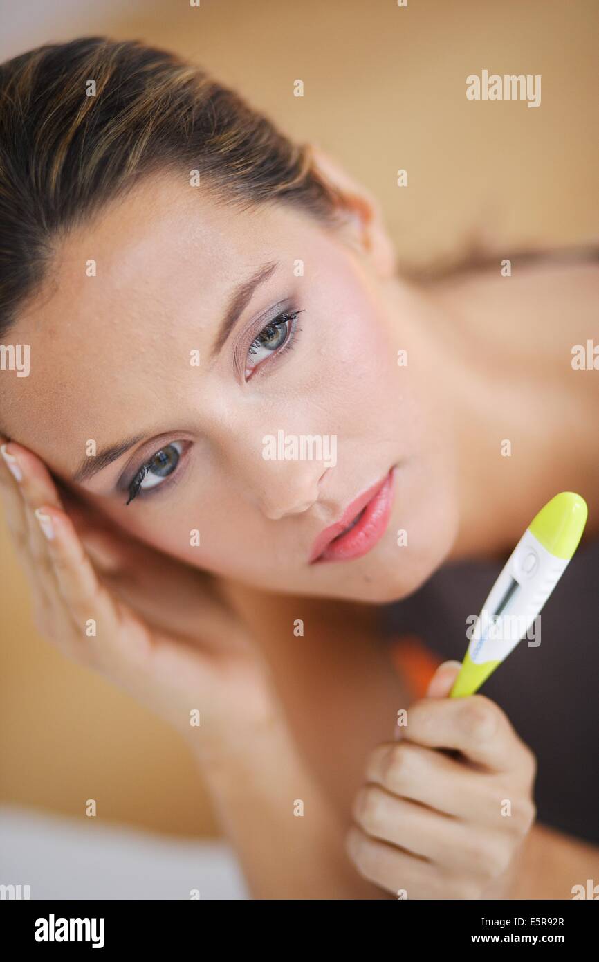 Woman checking her temperature with a digital thermometer. Stock Photo