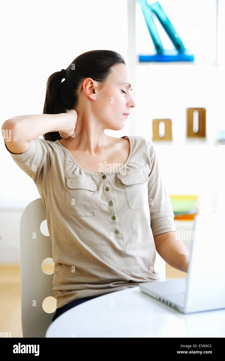 Woman suffering from neck pain in office Stock Photo - Alamy
