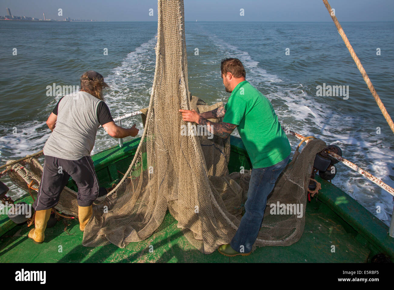 Fishermen preparing fish net on board of shrimp boat fishing for shrimps on the North Sea Stock Photo