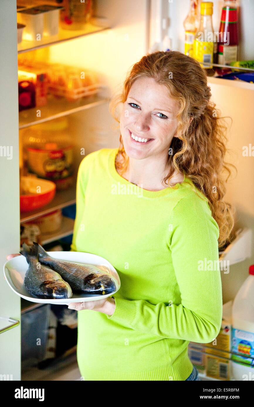 Woman taking fish out of the fridge. Stock Photo