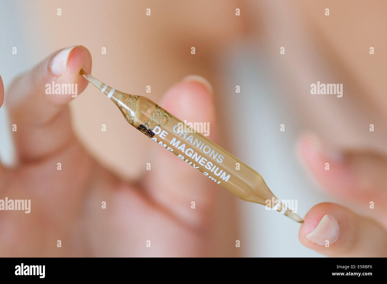 Woman holding a glass ampoule of magnesium. Stock Photo