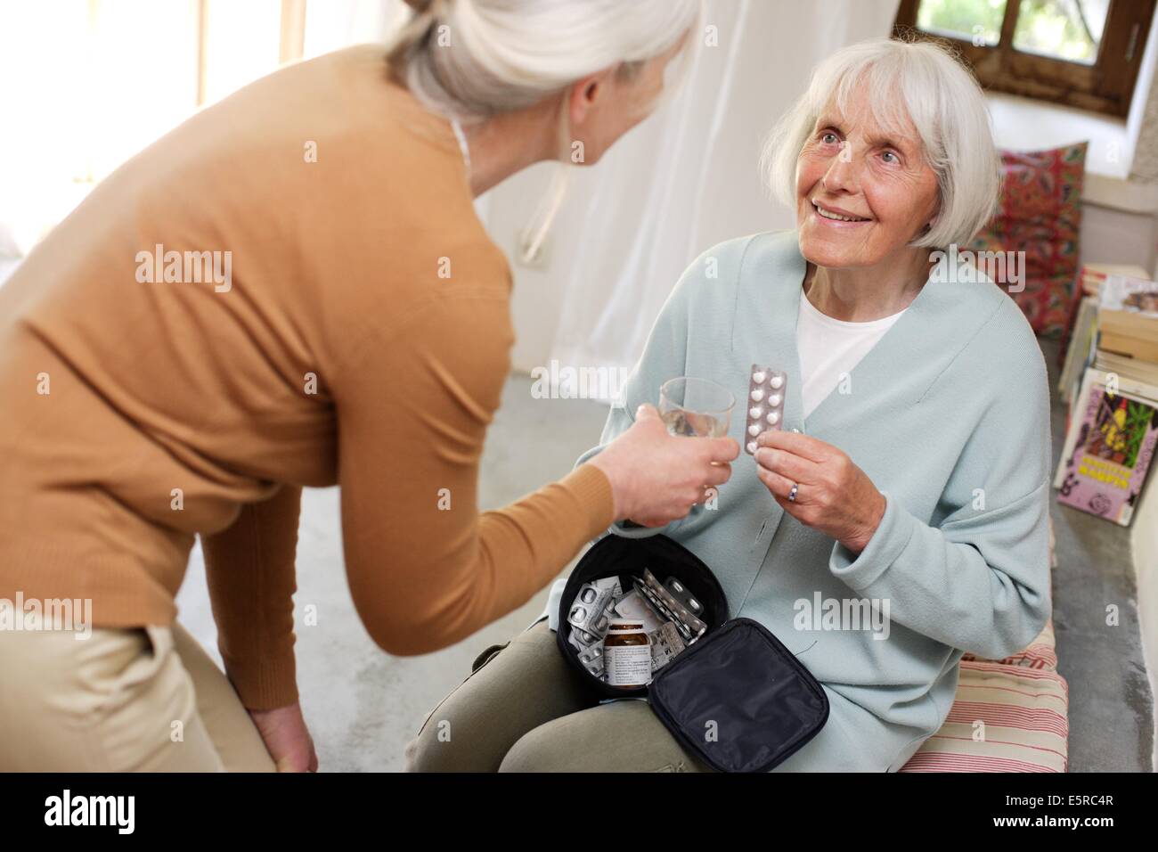 Woman helping elderly woman taking medicine Stock Photo Alamy