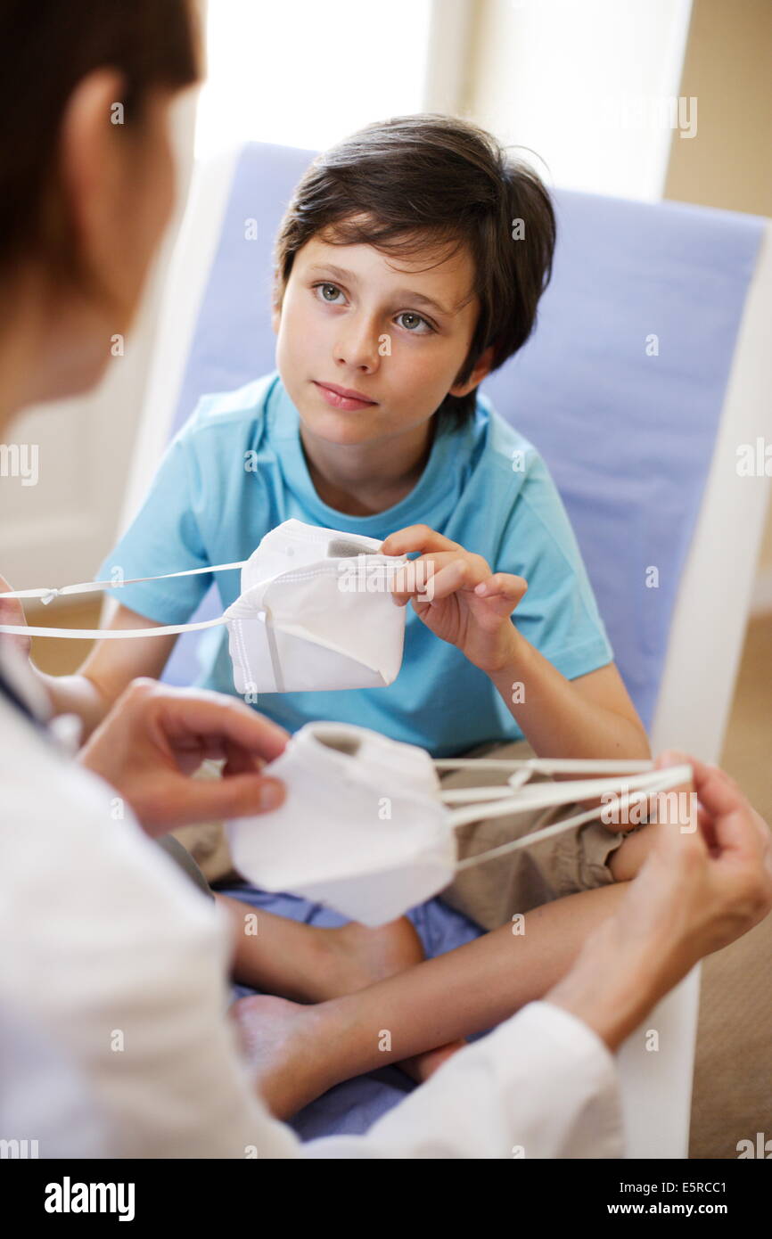 Doctor explains a 9 yearold boy how to use protective mask Stock Photo