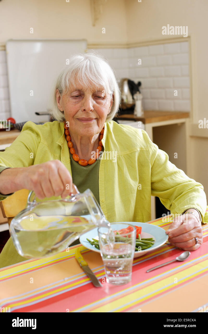 80 year old woman pouring a glass of water Stock Photo Alamy