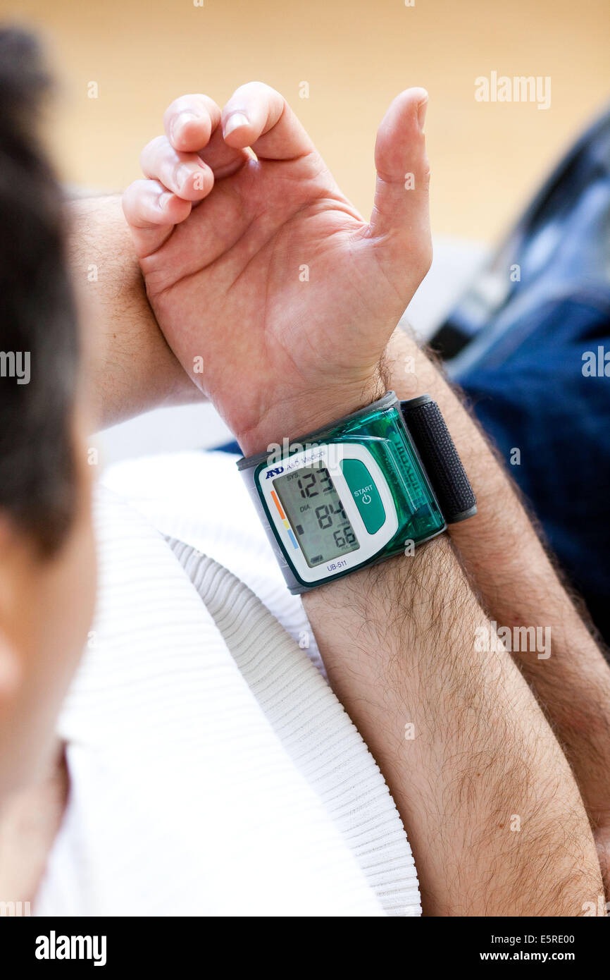 Man taking his blood pressure with a portable blood pressure monitor. Stock Photo