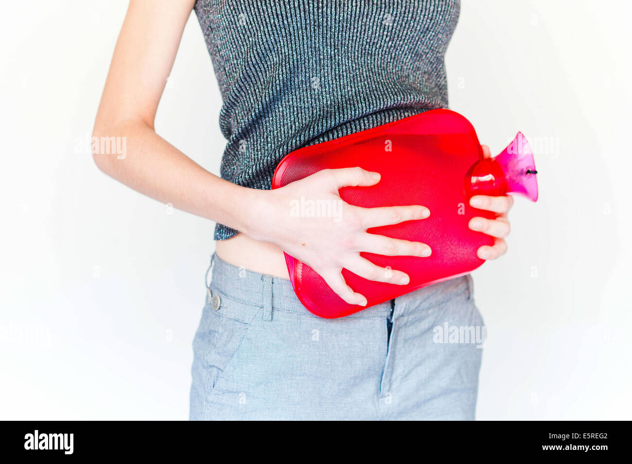 Woman using a hotwater bottle on her belly to releive abdominal pain