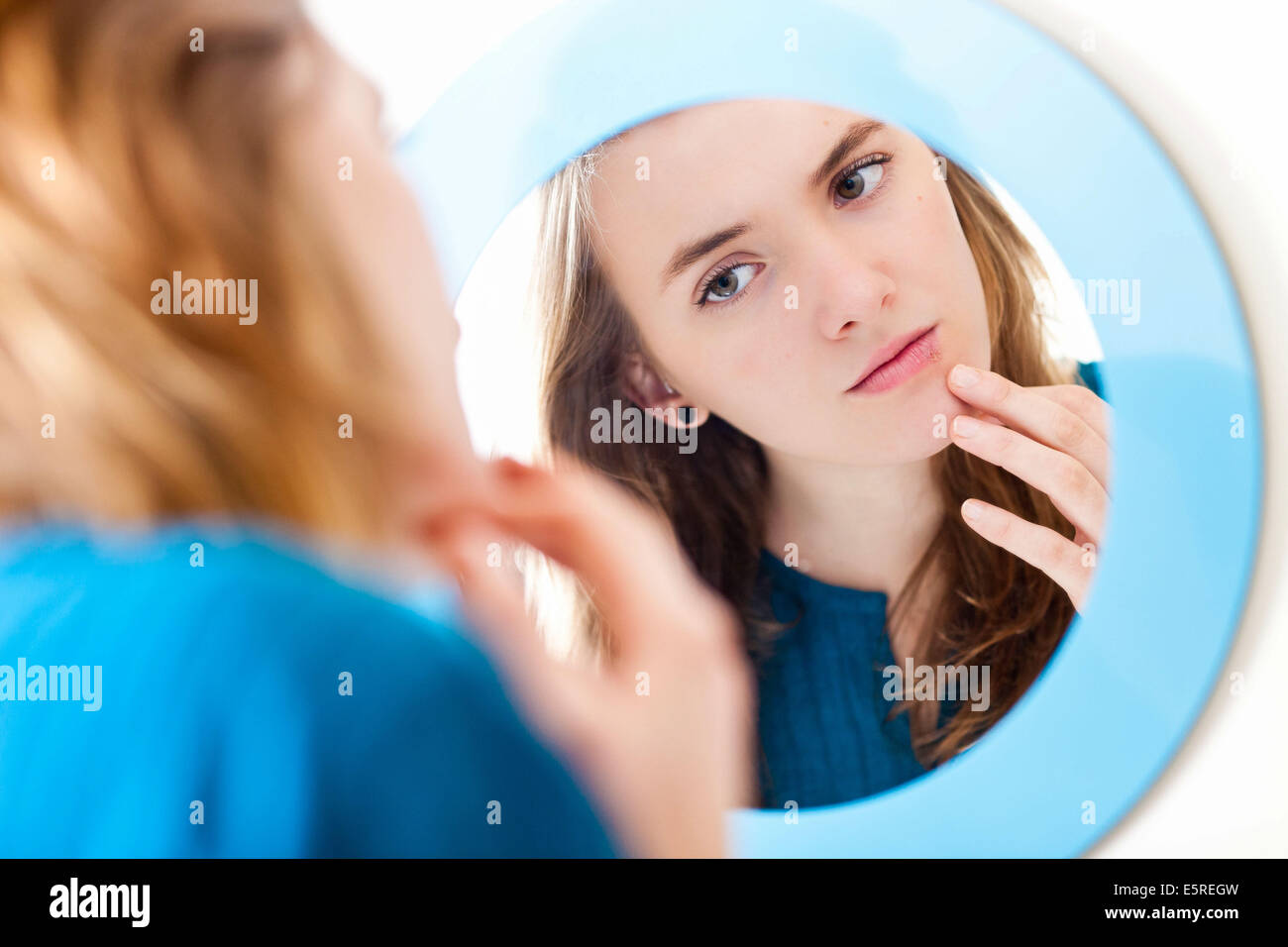 Young woman checking her face in the mirror Stock Photo Alamy