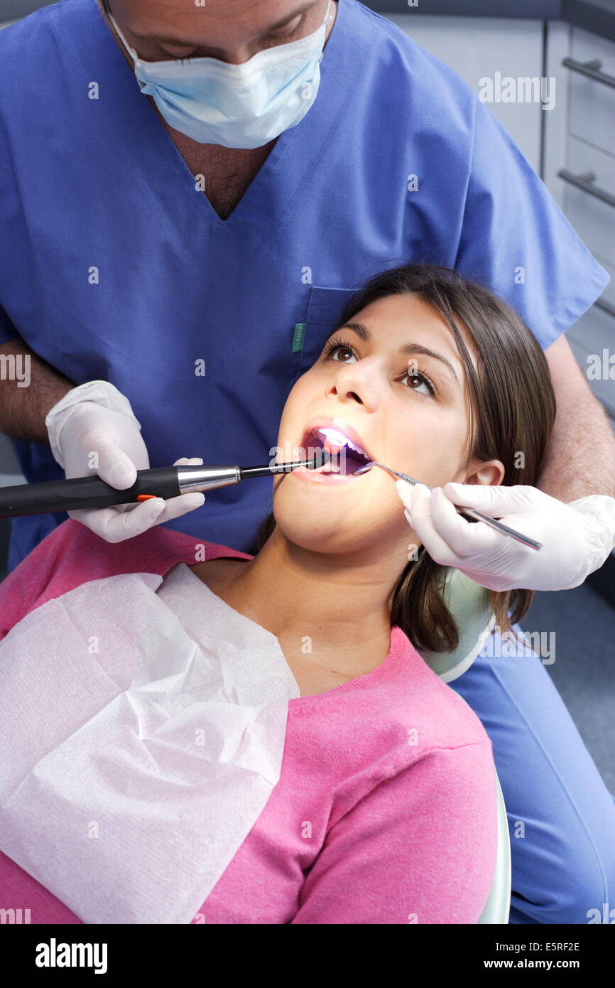Dentist using ultraviolet light to set a photosensitive amalgam (filling). Stock Photo