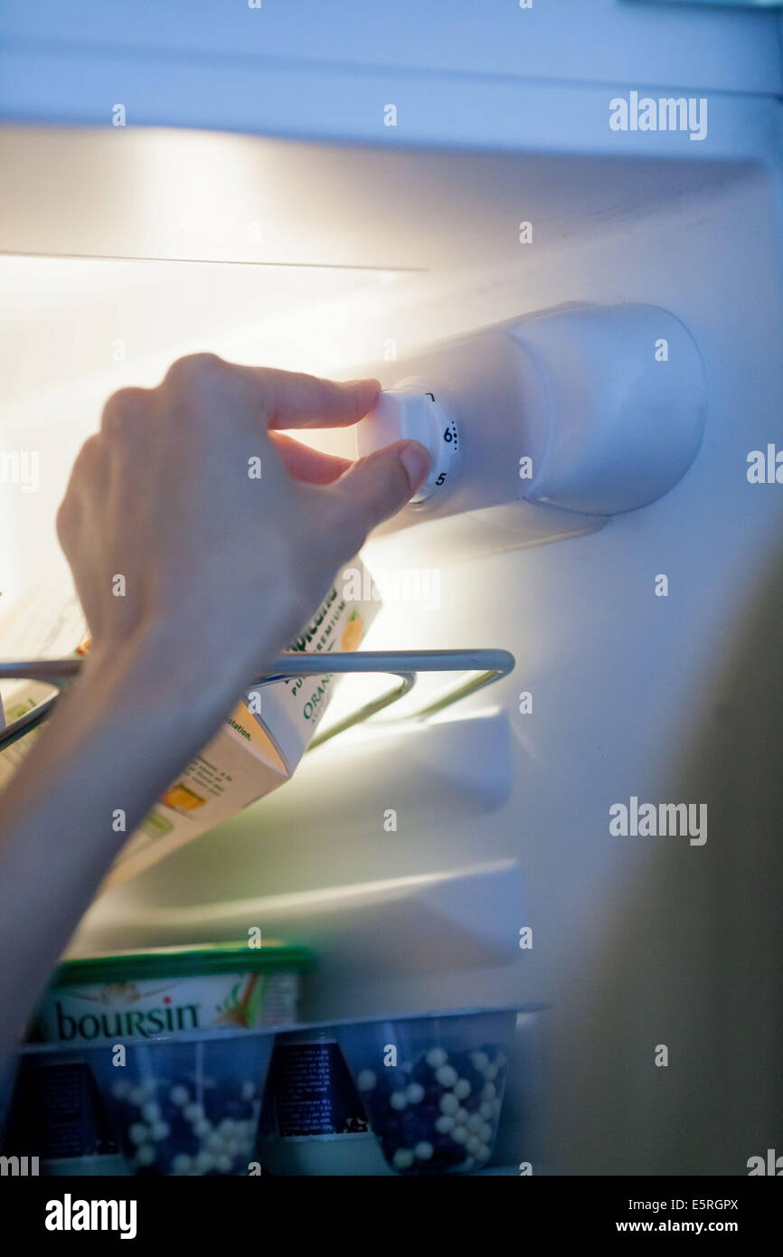 Woman setting the thermostat of a refrigerator. Stock Photo