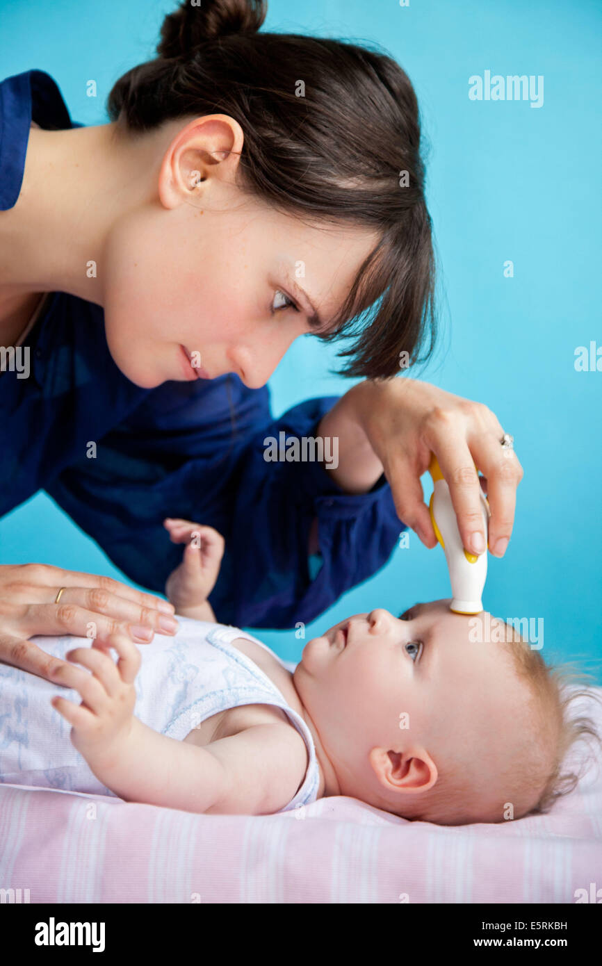 Checking the temperature of 5 month old baby with forehead thermometer