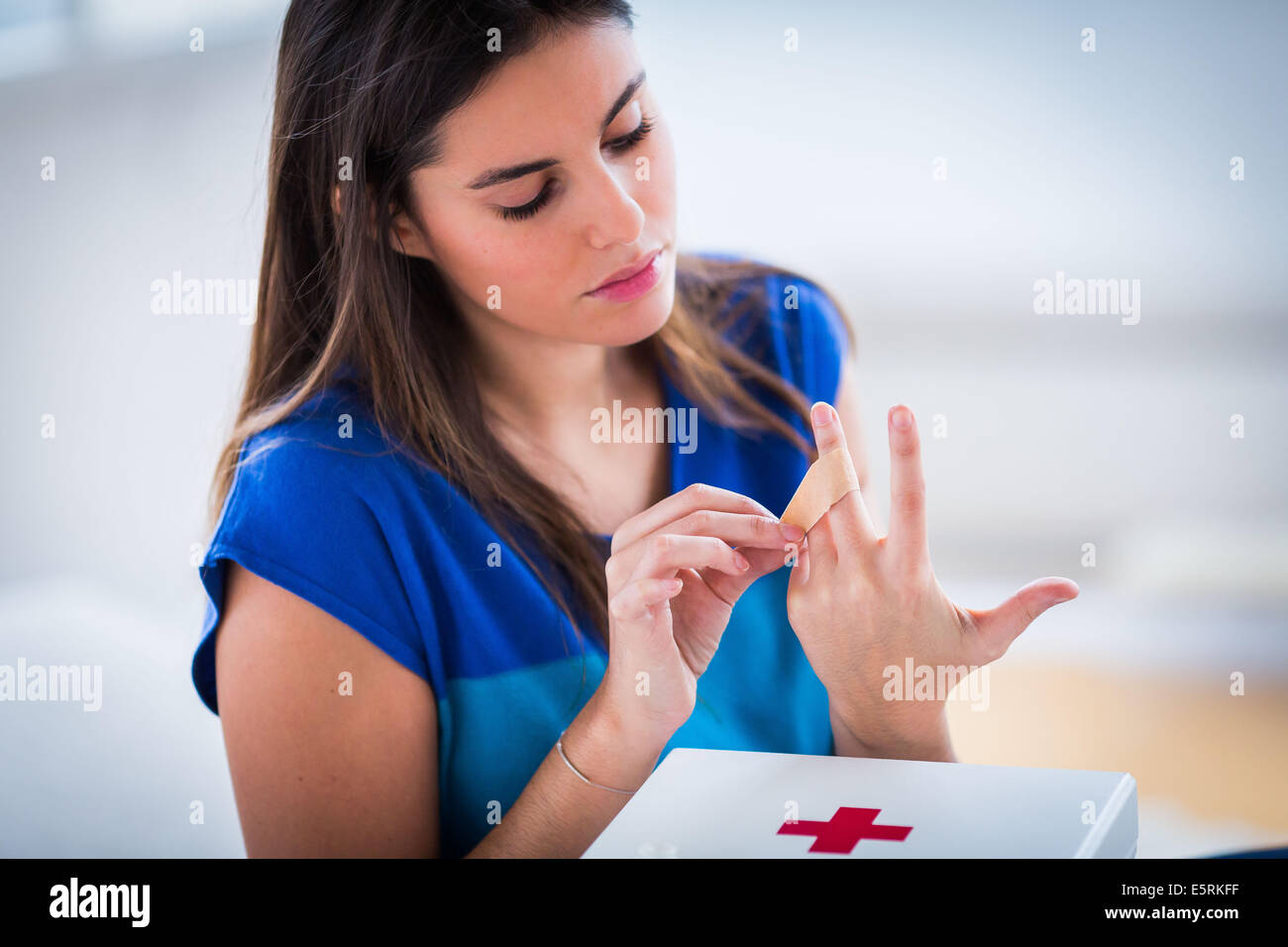 Woman putting a band-aid on her finger. Stock Photo