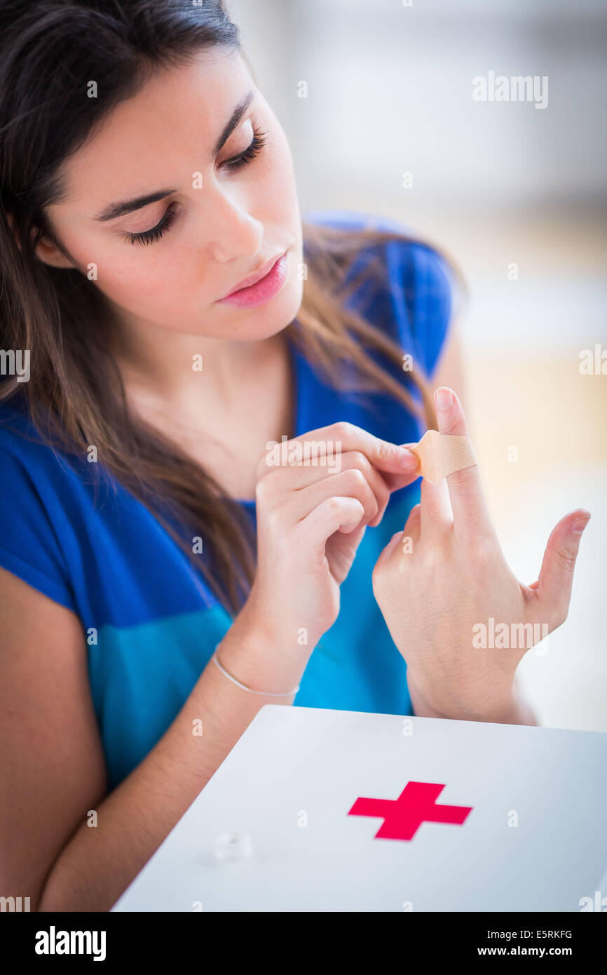 Woman putting a band-aid on her finger. Stock Photo