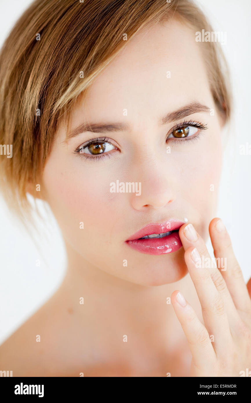 Woman applying cream on her lips as a treatment for a cold sore Stock