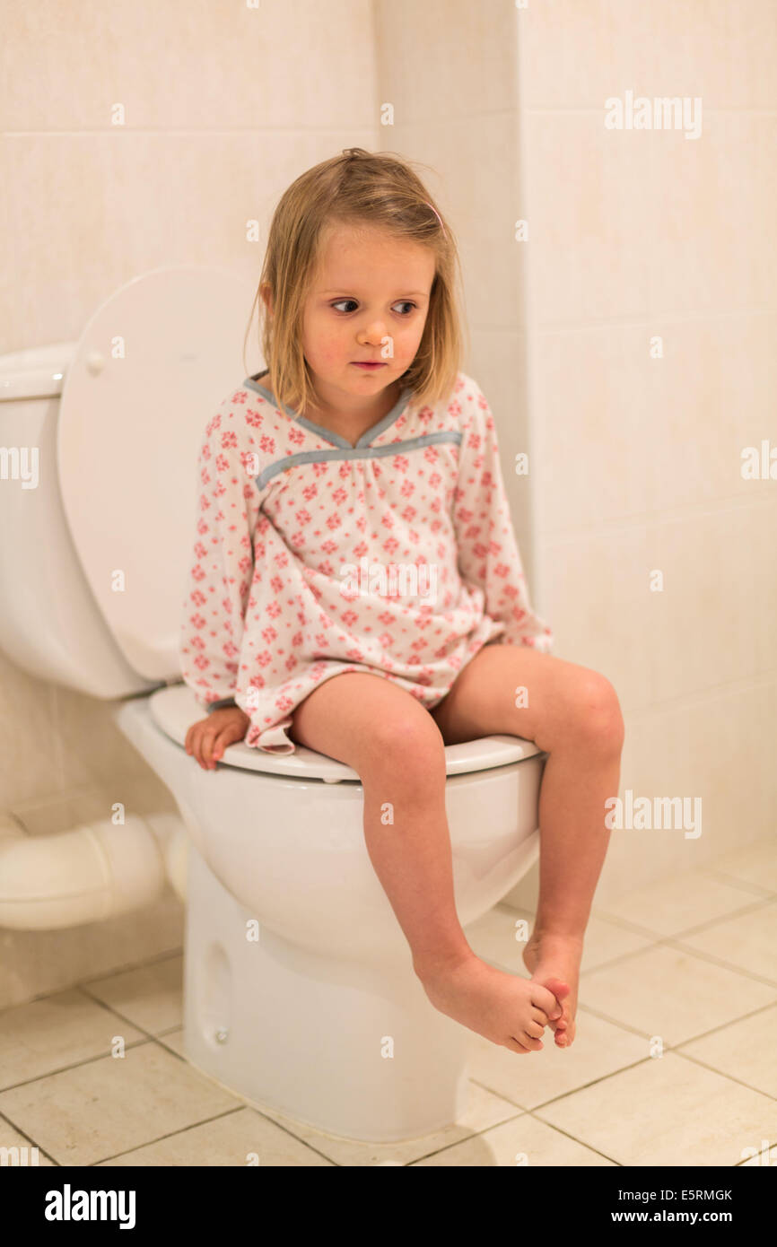 Toilet training. 3 year old girl using an adult toilet having progressed from the use of a child's potty. Stock Photo