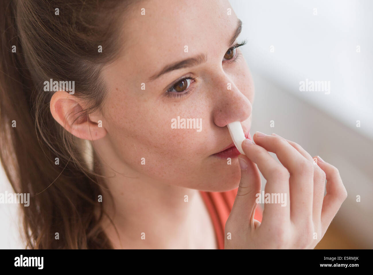 Woman using a sterile gauze soaked in hydrogen peroxide to stop a nosebleed. Stock Photo