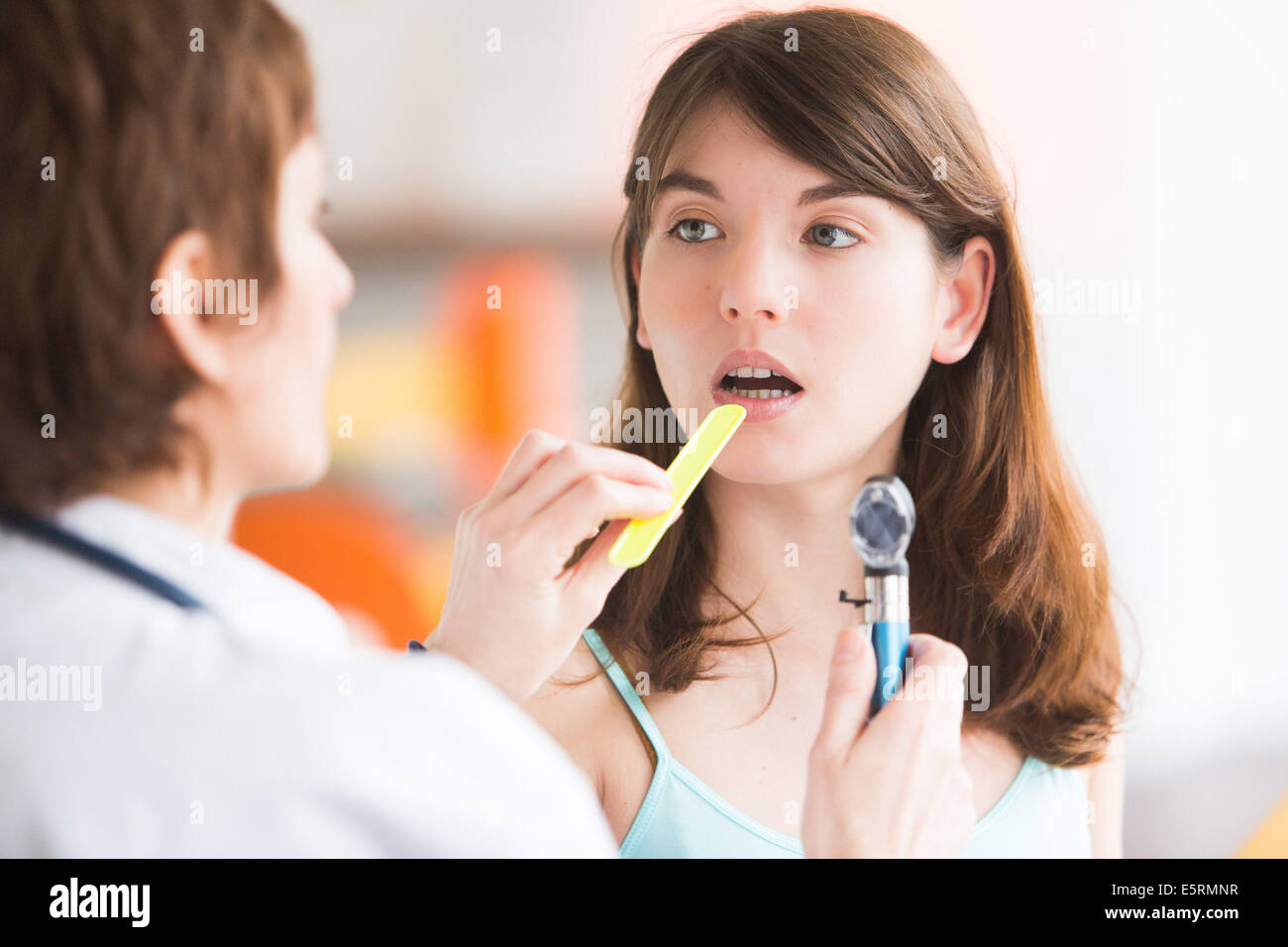 Female doctor using a tongue depressor to allow an examination of a