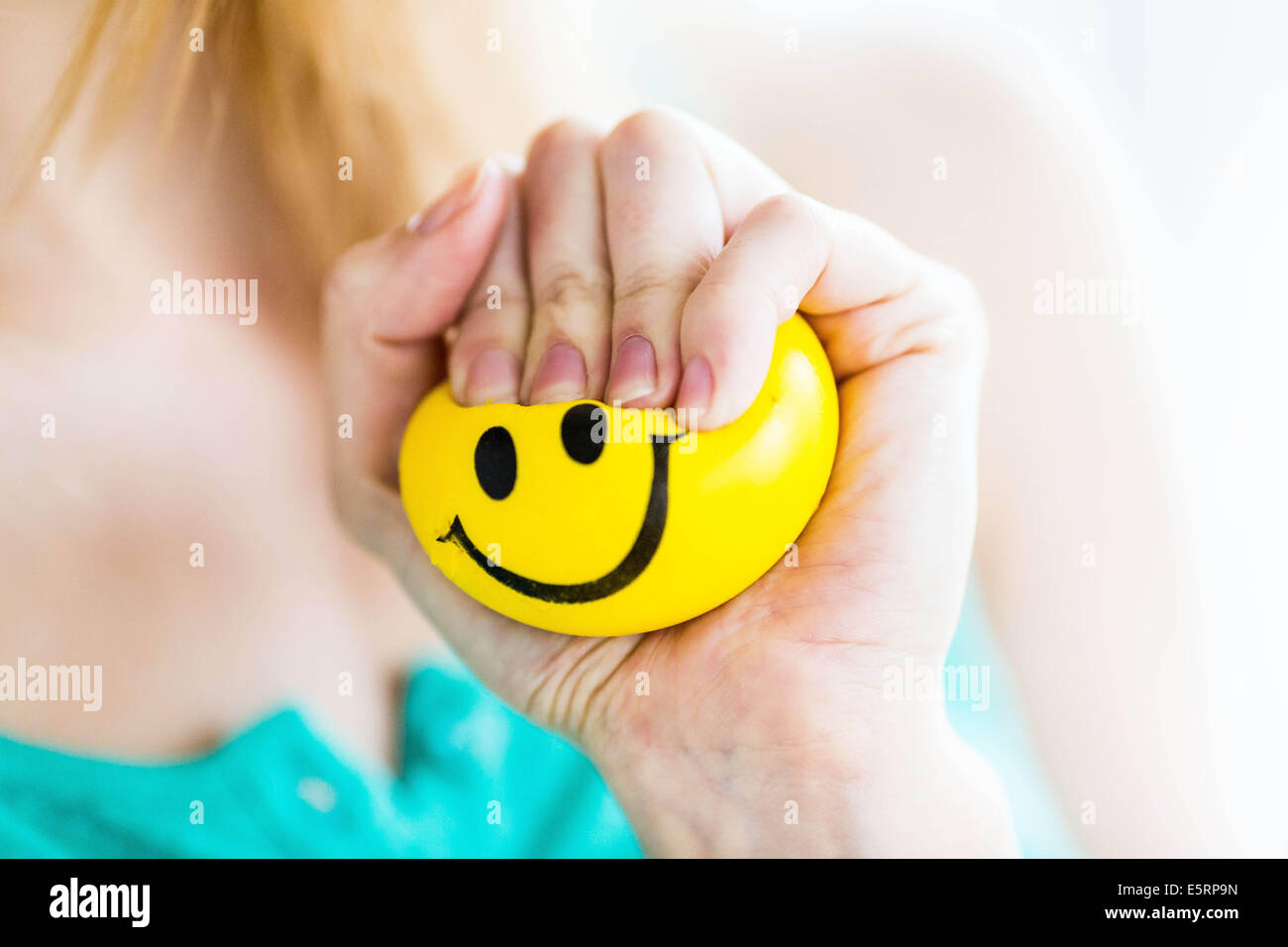Woman kneading a smiley stress ball. Stock Photo