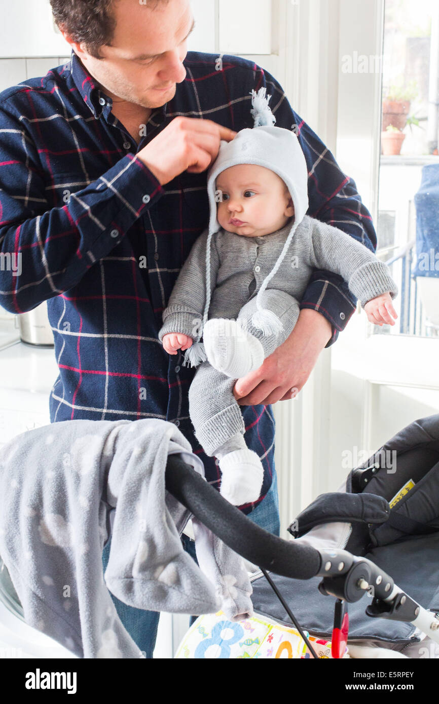 Father putting a cap to his 5-month-old baby boy. Stock Photo