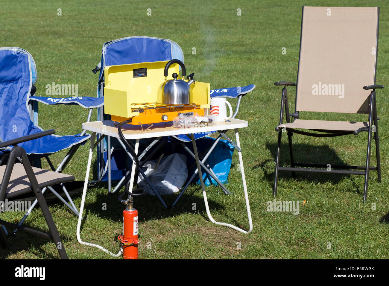 Picnic table and chairs with a portable stove and steaming kettle Stock Photo
